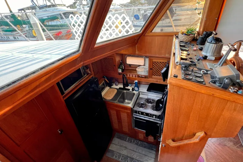 Slide: The Image of 1985 Heritage East 40 Sundeck Trawler kitchen with wooden cabinetry and nautical decor. - 22