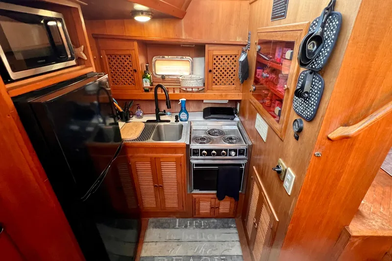 Slide: The Image of 1985 Heritage East 40 Sundeck Trawler kitchen with stove, sink, and wooden cabinetry. - 23