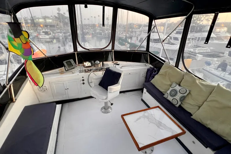 Slide: The Image of 1985 Heritage East 40 Sundeck interior with helm, seating, and marina view. - 63