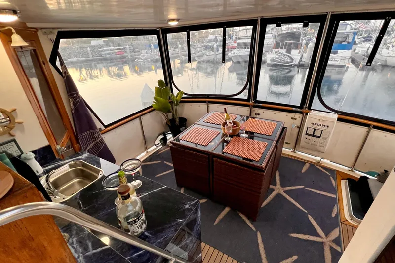 Slide: The Image of Interior of 1985 Heritage East 40 Sundeck Trawler with marina view, featuring dining area and kitchenette. - 66