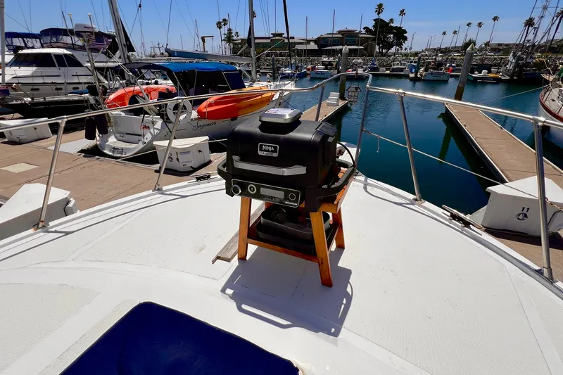 Slide: The Image of 1985 Heritage East 40 Sundeck Trawler with grill, docked at marina with boats and clear sky. - 9