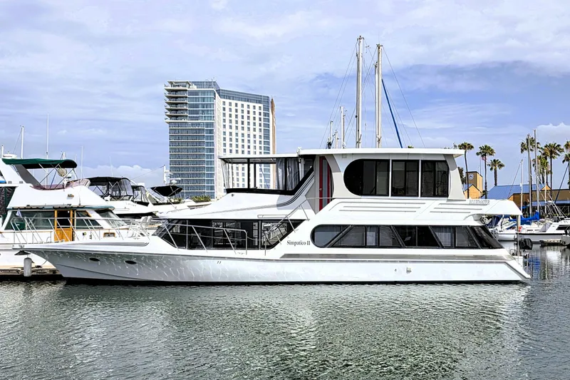 The Image of 1991 Bluewater Yachts 5900 Coastal Cruiser docked in marina, modern building in background. - 0