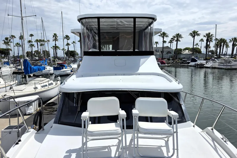 Slide: The Image of 1991 Bluewater Yachts 5900 Coastal Cruiser docked in a marina with palm trees. - 23