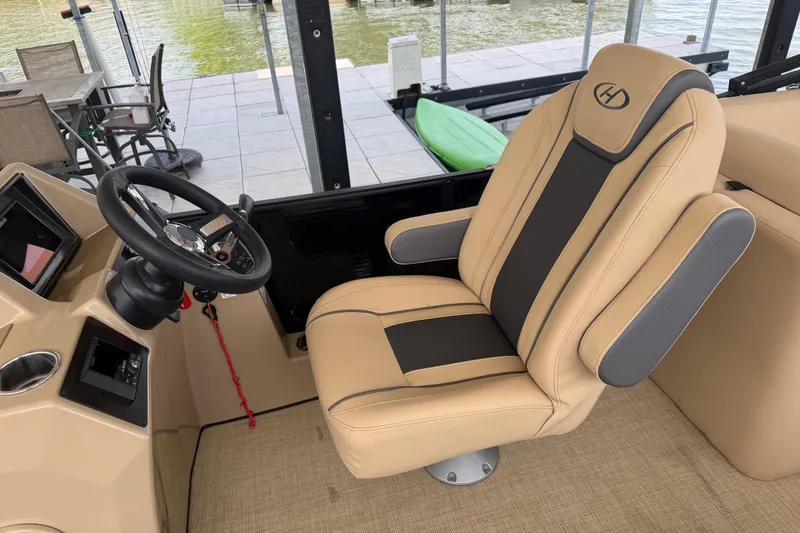 Slide: The Image of 2023 Harris Cruiser 250 CW boat interior with beige captain's chair and steering wheel. - 11