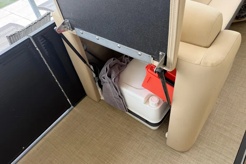 Slide: The Image of 2023 Harris Cruiser 250 CW storage compartment with cooler and red container. - 18