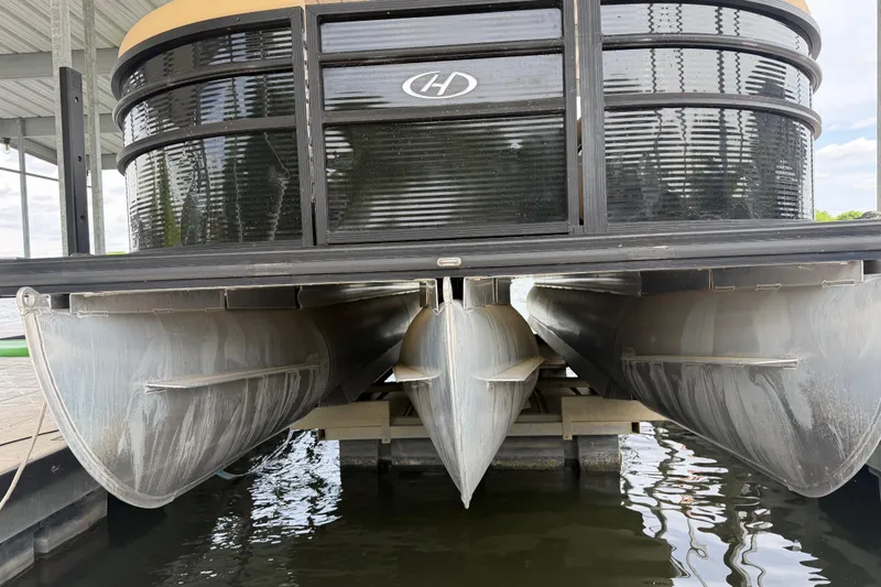 Slide: The Image of 2023 Harris Cruiser 250 CW pontoon boat docked, showing pontoons and hull design. - 4