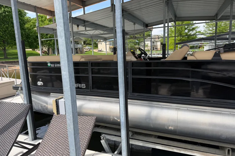 Slide: The Image of 2023 Harris Cruiser 250 CW pontoon boat docked under a covered marina. - 6