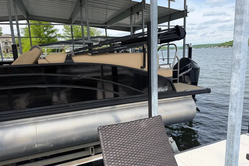 Slide: The Image of 2023 Harris Cruiser 250 CW pontoon boat docked on a serene lake. - 7