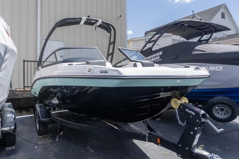 The Image of 2026 Yamaha Boats AR195 on trailer, parked outdoors near other boats. - 1
