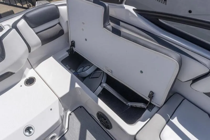 Slide: The Image of 2026 Yamaha Boats AR195 interior storage compartment with open seat and speaker. - 21