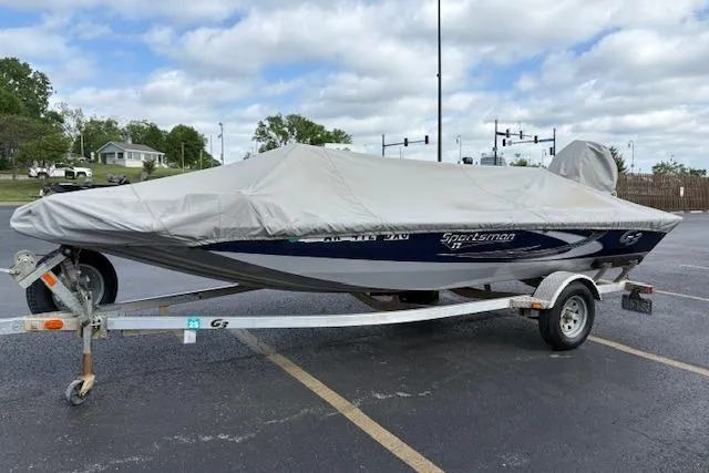 Slide: The Image of 2017 G3 Sportsman 1710 Vinyl boat covered on a trailer in a parking lot. - 2
