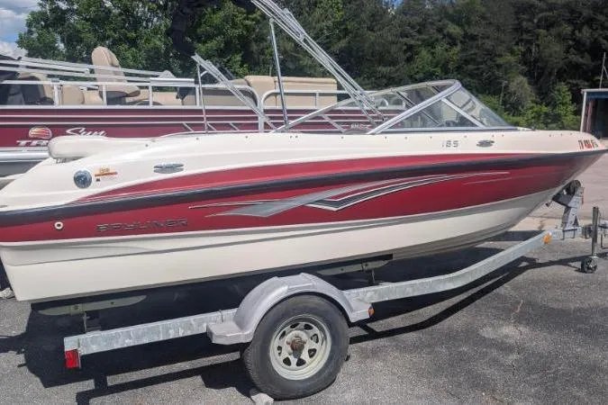 Slide: The Image of 2010 Bayliner 185 Bowrider boat on trailer, red and white design, parked outdoors. - 10