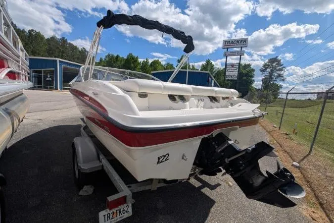 Slide: The Image of 2010 Bayliner 185 Bowrider on trailer, parked outdoors under a partly cloudy sky. - 3