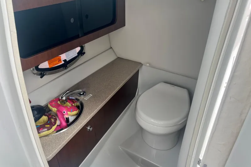 Slide: The Image of 2018 Crownline 285 SS boat bathroom with sink, toilet, and storage cabinet. - 12