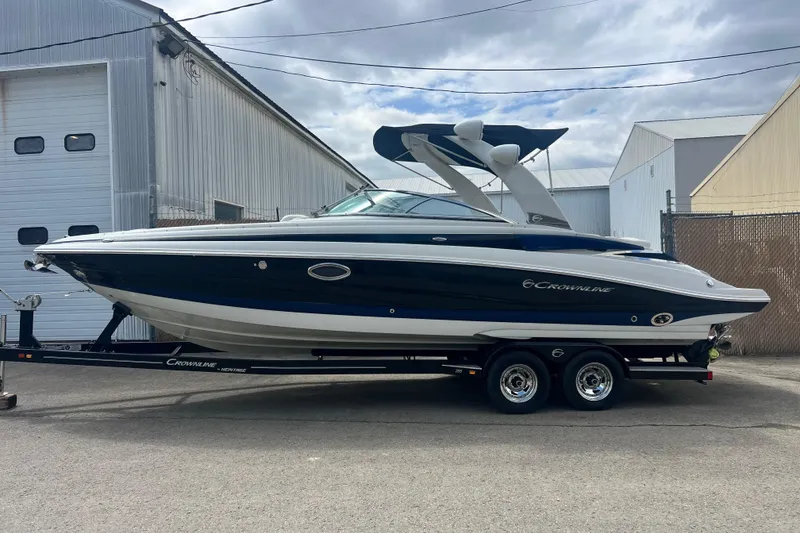 Slide: The Image of 2018 Crownline 285 SS boat on trailer, parked outside industrial building. - 2