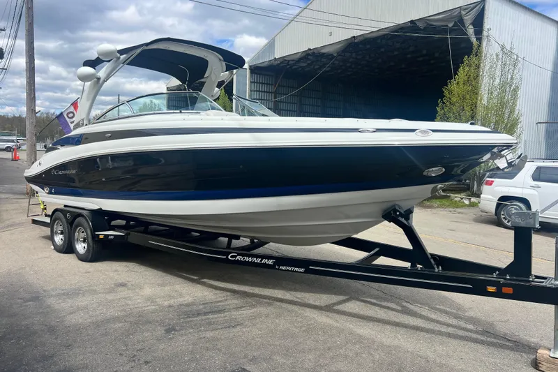 Slide: The Image of 2018 Crownline 285 SS boat on trailer, parked outdoors near a warehouse. - 6