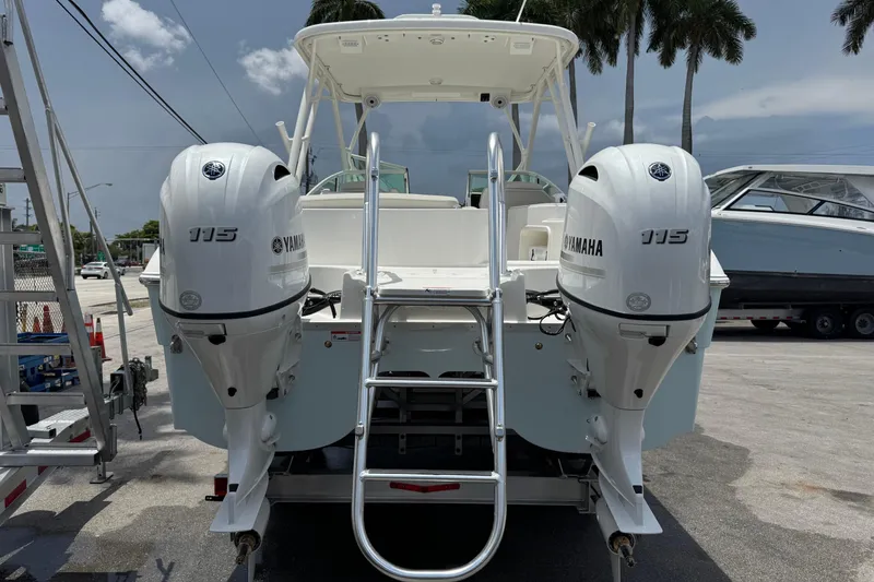Slide: The Image of 2026 World Cat 230 SD boat with twin Yamaha 115 engines, docked under palm trees. - 5