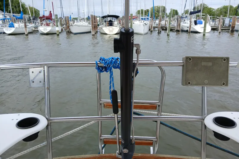 Slide: The Image of 1983 Sabre 34 sailboat stern view with marina backdrop, featuring railing and mooring lines. - 3