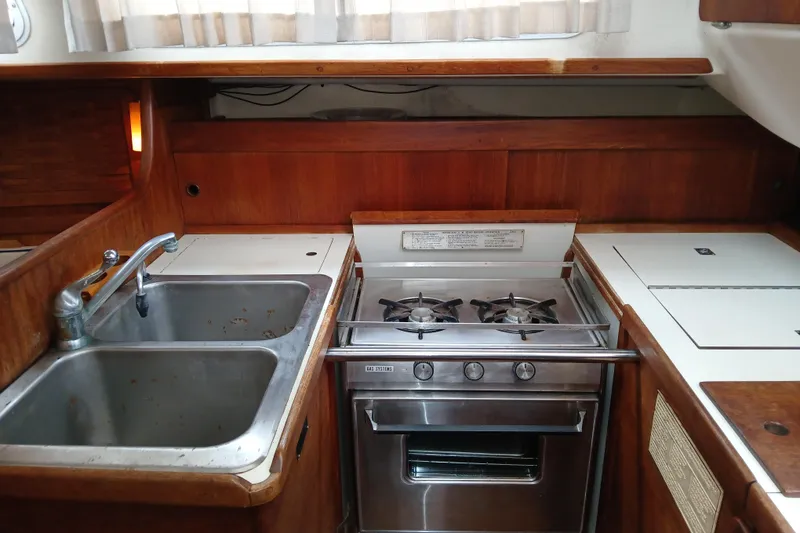 Slide: The Image of 1983 Sabre 34 yacht kitchen with stainless steel sink and stove, wooden cabinetry. - 5