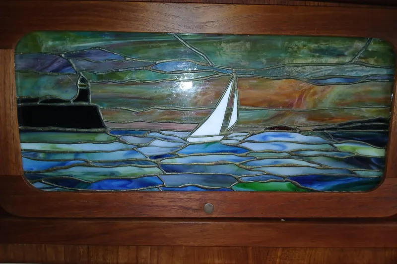 Slide: The Image of Stained glass artwork depicting a sailboat on the sea, set in a wooden frame. - 6