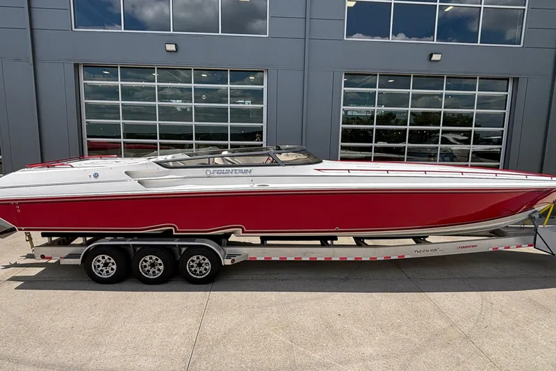 Slide: The Image of 2007 Fountain 42 Lightning speedboat in red and white on a trailer, parked outside a garage. - 2