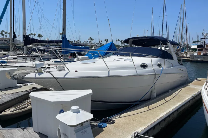 The Image of 2000 Monterey 302 Cruiser docked at a marina, surrounded by sailboats under a clear blue sky. - 0