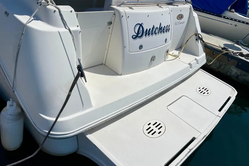 Slide: The Image of Rear view of a 2000 Monterey 302 Cruiser boat named "Dutchess" docked at a marina. - 2