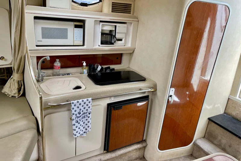 Slide: The Image of Compact kitchen area in a 2000 Monterey 302 Cruiser boat, featuring a microwave and sink. - 21