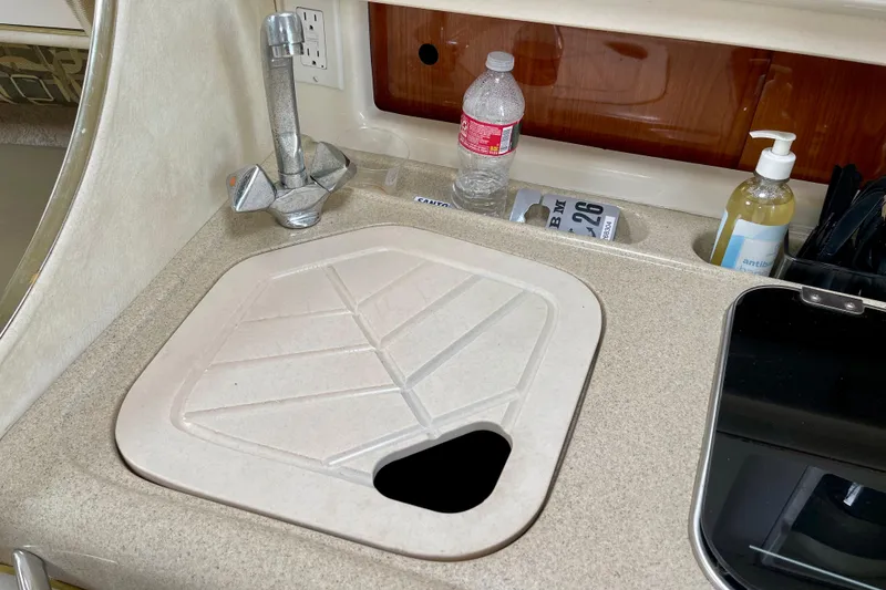 Slide: The Image of Kitchen sink area in a 2000 Monterey 302 Cruiser boat with faucet and countertop items. - 24