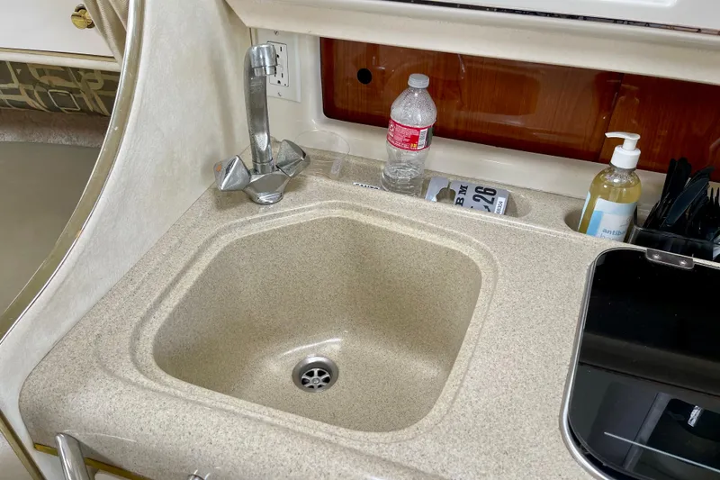 Slide: The Image of Kitchen sink area in a 2000 Monterey 302 Cruiser boat with faucet and countertop items. - 25