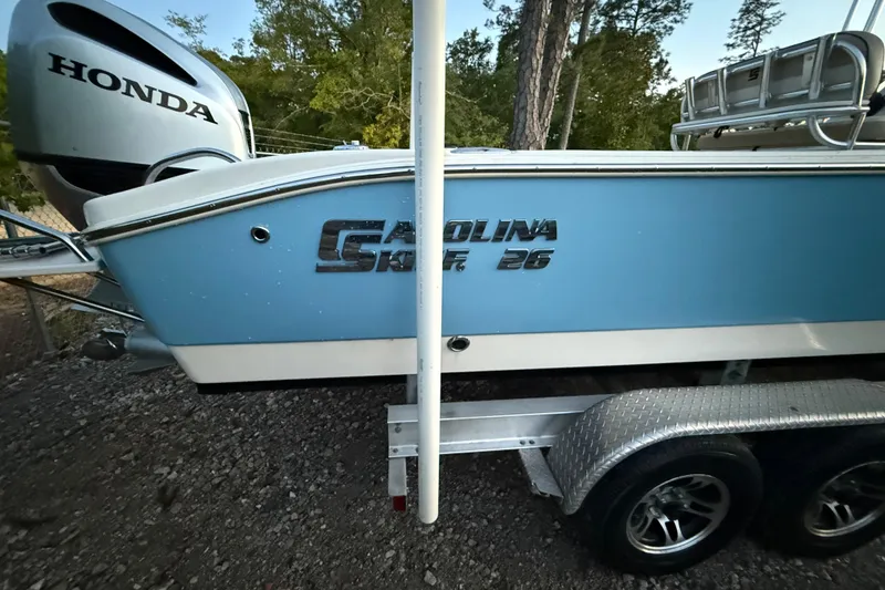 Slide: The Image of 2021 Carolina Skiff 26 Ultra Elite boat with T-top, parked near storage units. - 15