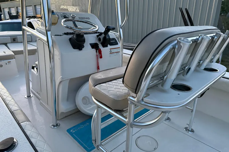 Slide: The Image of 2021 Carolina Skiff 26 Ultra Elite boat interior with seating and console, parked near storage units. - 19
