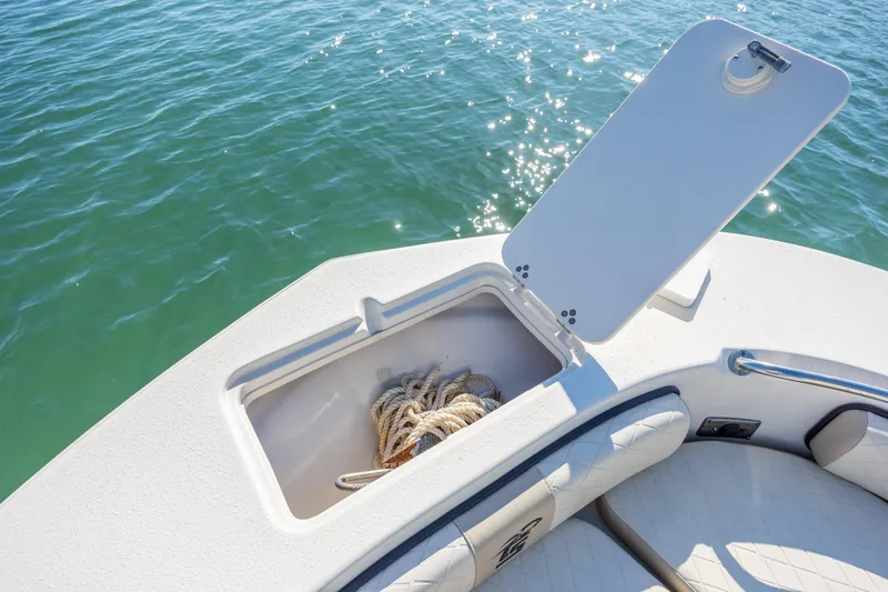 Slide: The Image of 2021 Carolina Skiff 26 Ultra Elite boat with open storage compartment on calm water. - 25