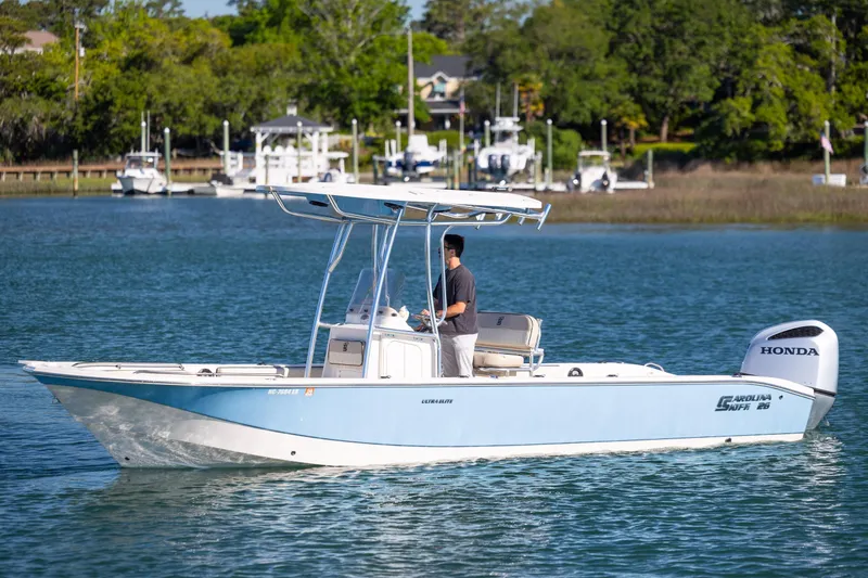 Slide: The Image of 2021 Carolina Skiff 26 Ultra Elite boat cruising on a serene lake with lush greenery. - 28