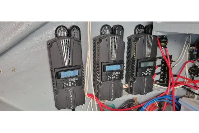 Slide: The Image of Three black charge controllers with digital displays and wiring on a Tayana Isara 50, 2014 model. - 102