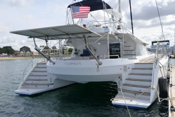 Slide: The Image of 2014 Tayana Isara 50 catamaran docked, featuring spacious deck and American flag. - 106