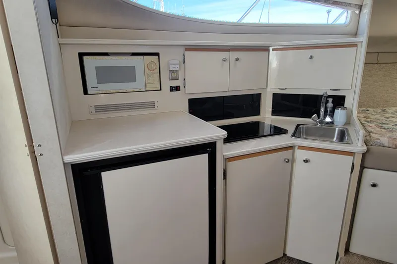 Slide: The Image of 1999 Bayliner 3055 Ciera Sunbridge interior kitchen with microwave, sink, and storage cabinets. - 20