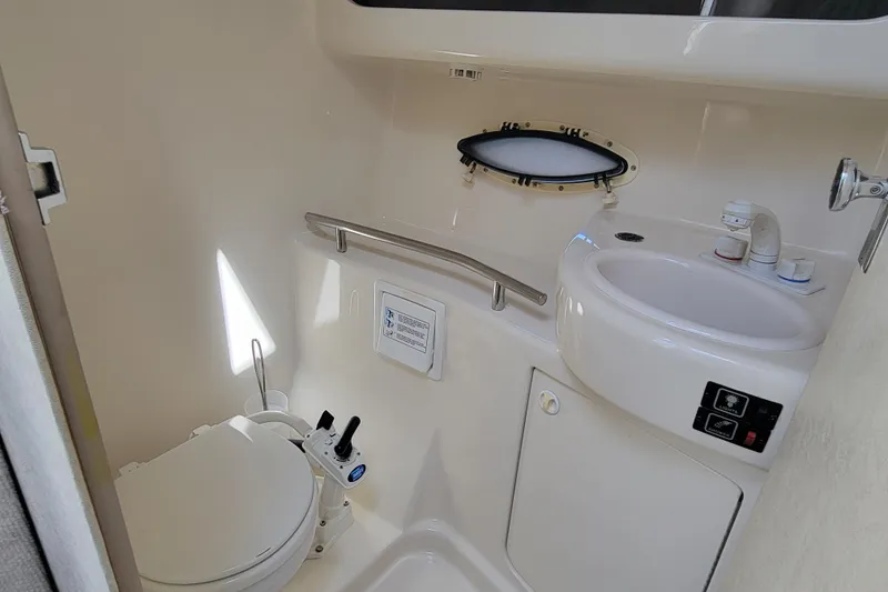 Slide: The Image of 1999 Bayliner 3055 Ciera Sunbridge bathroom with toilet, sink, and porthole window. - 23