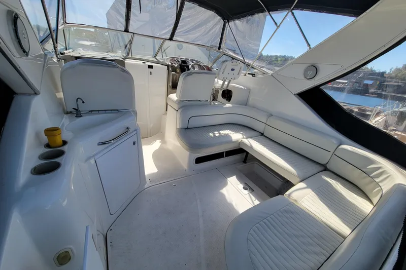 Slide: The Image of 1999 Bayliner 3055 Ciera Sunbridge interior with white seating and helm, docked by water. - 8