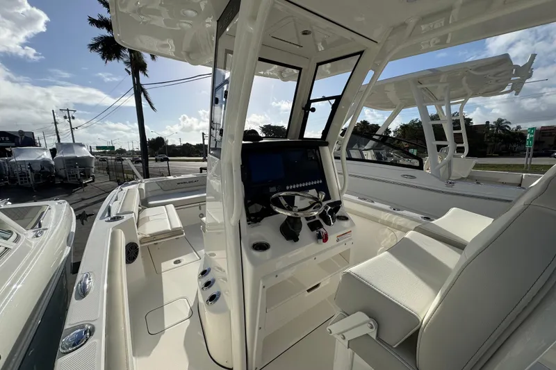 Slide: The Image of 2026 World Cat 235 TE boat interior with modern helm and seating, parked outdoors. - 7