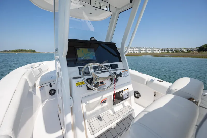 Slide: The Image of 2025 Sea Fox 228 Commander boat interior with steering wheel and navigation system on calm water. - 17