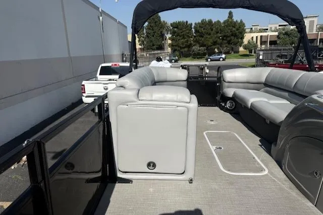 Slide: The Image of 2018 Regency 254 LE3 pontoon boat with spacious seating and canopy in a parking area. - 11