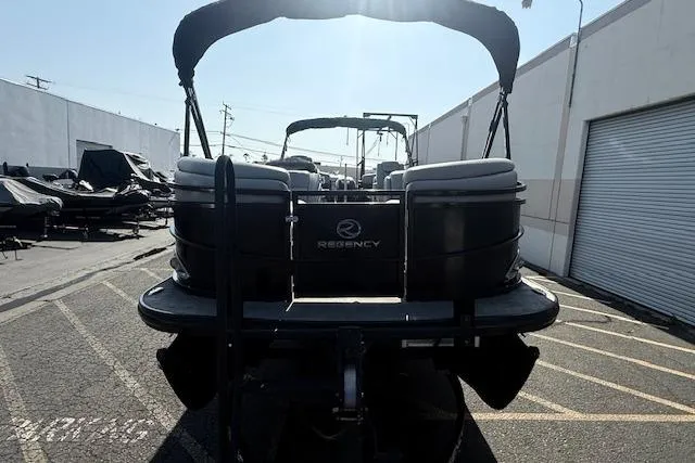 Slide: The Image of 2018 Regency 254 LE3 pontoon boat parked in a lot, rear view. - 2