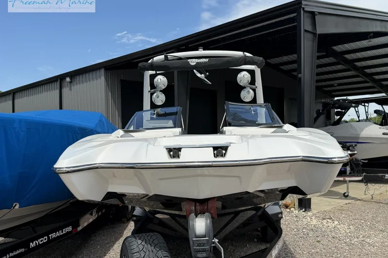 Slide: The Image of 2019 Malibu Wakesetter 24 MXZ boat on trailer, parked outdoors near a covered area. - 5