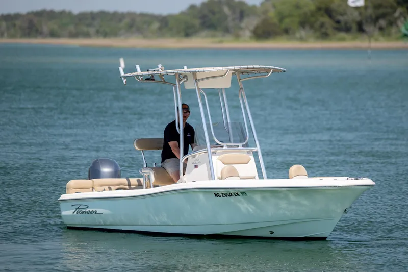 Slide: The Image of 2019 Pioneer 180 Islander boat cruising on a calm lake with a person at the helm. - 4