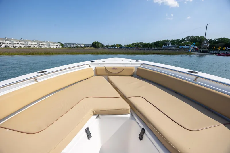 Slide: The Image of 2018 Sea Hunt Ultra 235 SE boat with tan seating, docked near waterfront buildings. - 12