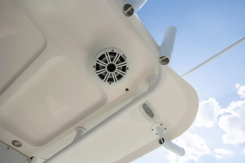 Slide: The Image of 2018 Sea Hunt Ultra 235 SE boat ceiling with speaker, rod holders, and blue sky background. - 18
