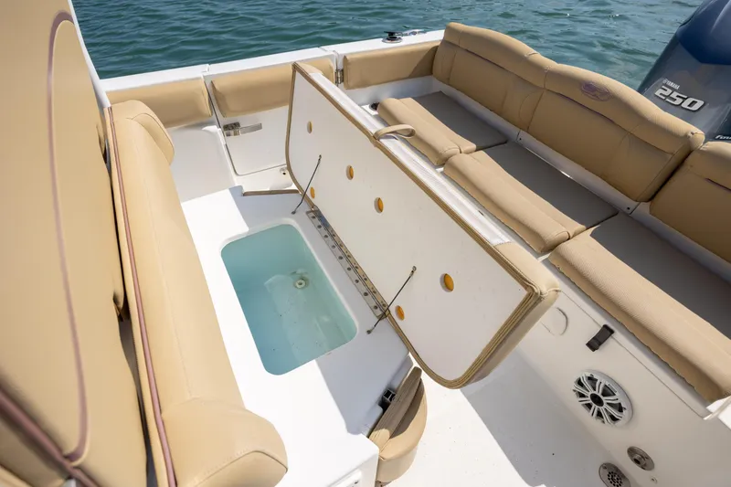 Slide: The Image of 2018 Sea Hunt Ultra 235 SE boat interior with tan seating and open storage compartment. - 19