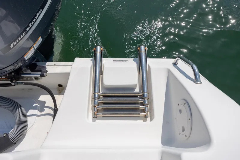 Slide: The Image of 2018 Sea Hunt Ultra 235 SE boat ladder and motor, docked on water. - 24