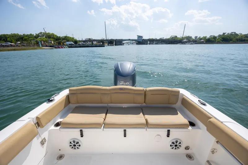 Slide: The Image of 2018 Sea Hunt Ultra 235 SE boat interior with seating, overlooking calm waters and distant bridge. - 25